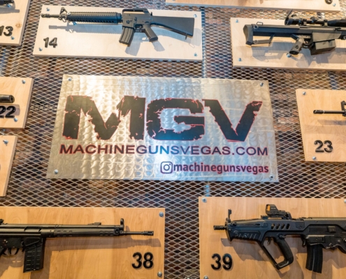 Numbered rifles mounted on the wall around the MGV machinegunsvegas.com sign in the Machine Guns Vegas lounge