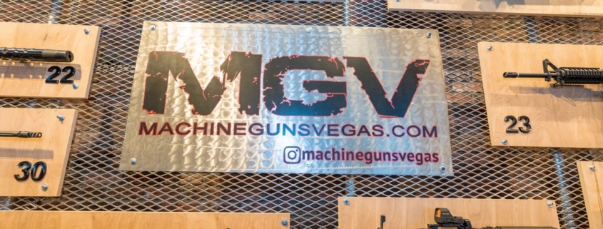 Numbered rifles mounted on the wall around the MGV machinegunsvegas.com sign in the Machine Guns Vegas lounge